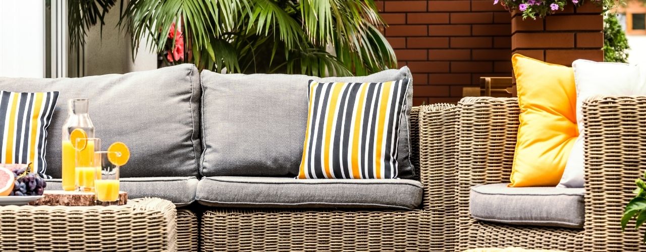 Outdoor patio furniture with gray cushions and yellow and blue striped pillows.
