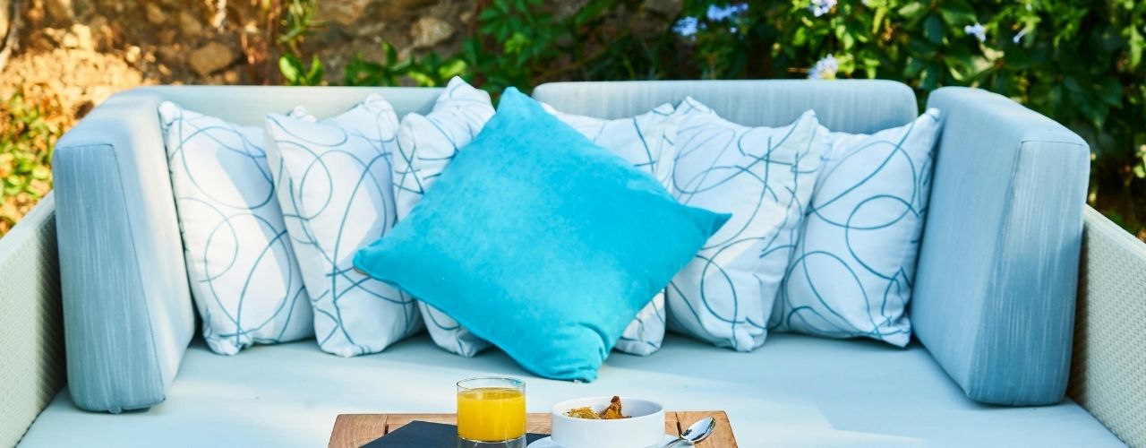 Outdoor sofa with blue and white patterned cushions on a sunny day.